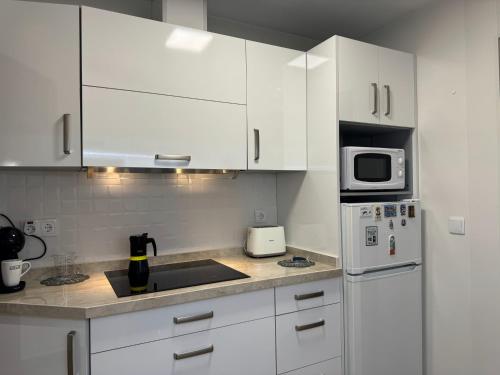 贝纳尔马德纳Apartamento Mar del Sur的白色的厨房配有白色的橱柜和微波炉