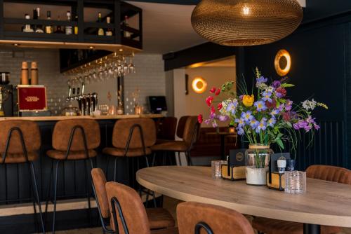 霍勒姆Hotel-Brasserie De Walvisvaarder的餐厅设有一张带鲜花的木桌