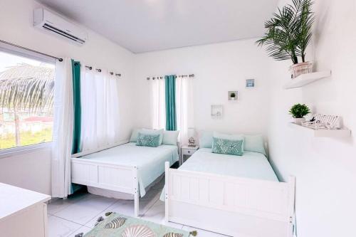 特拉Atlantis Luxury Villages - Neptun的白色的客房设有两张床和窗户。