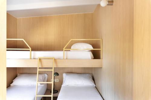 圣塞瓦斯蒂安Wecamp San Sebastián的客房内的2张双层床和白色枕头