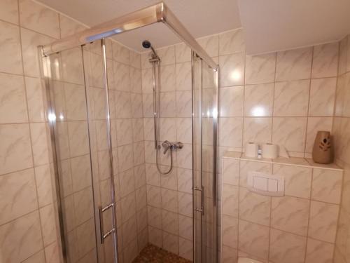 瓦尔内明德克斯廷宾馆的浴室里设有玻璃门淋浴
