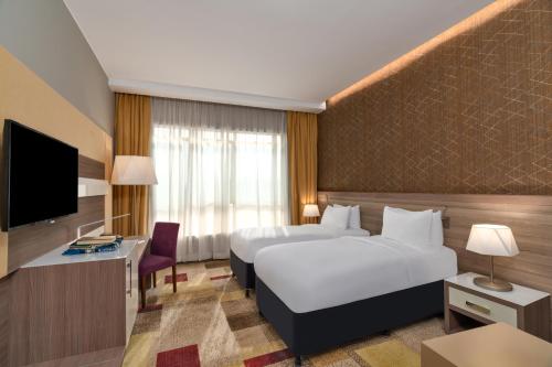 麦加Mercure Makkah Aziziah的酒店客房设有两张床和电视。