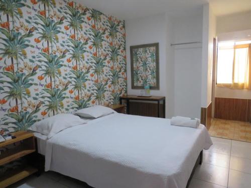 巴拿马城哥斯达旅馆酒店的卧室配有白色床和花卉壁纸