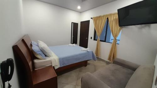 马里基塔Katara Boutique Hotel的一间卧室配有一张床、一台电视和一张沙发