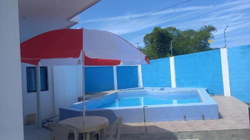 通苏帕Casa Tonsupa的一个带红色遮阳伞和桌子的游泳池
