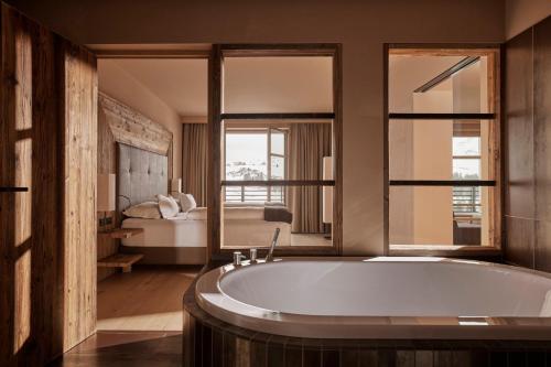 阿尔卑斯休斯山COMO Alpina Dolomites的带浴缸的浴室和1间带1张床的卧室