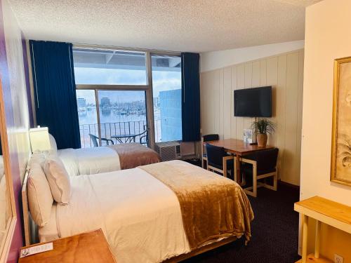 洛杉矶Foghorn Harbor Inn的酒店客房设有两张床、一张书桌和一个窗户。