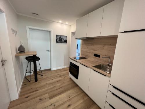 于斯德Dünen Lodge 2的厨房铺有木地板,配有白色橱柜。