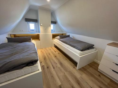 于斯德Dünen Lodge 6的一间卧室设有两张床,铺有木地板。