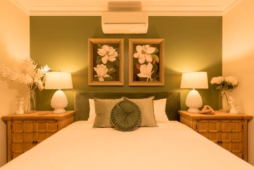 马莱尼墨兰莉酒店 的一间卧室配有一张带两盏灯和鲜花的床。