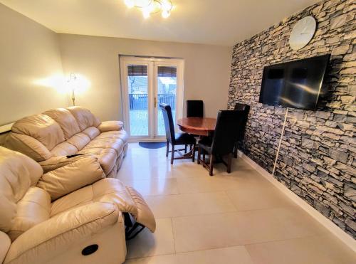 IdleHigh Rigg House Bradford - Luxury Accomodation with Private Parking的客厅配有沙发和石墙电视。