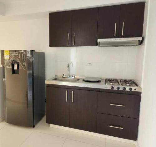 库库塔Apartamento con excelente vista的厨房配有棕色橱柜和不锈钢冰箱