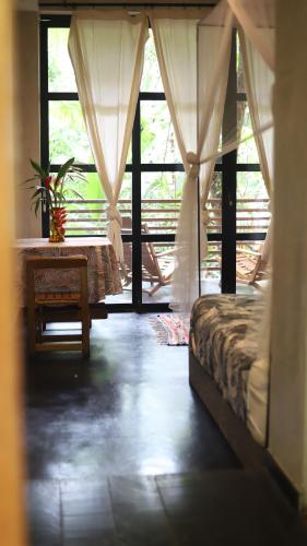 马尔多纳多港Kapievi Ecovillage的一间卧室配有一张床、一张桌子和一个窗户。