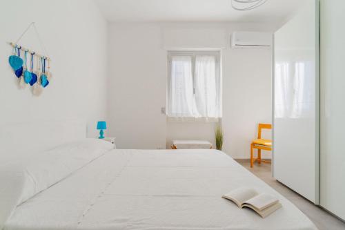 加利波利Terrazza vista mare e box auto的白色卧室配有一张大床,上面有书