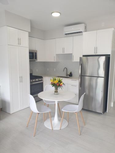 西湾Modern 1 bedroom walking distance to the beach!的厨房配有白色的桌椅和冰箱。