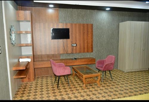 穆克缇斯瓦Hotel Pearl Residency的配有书桌和2把粉红色椅子的房间