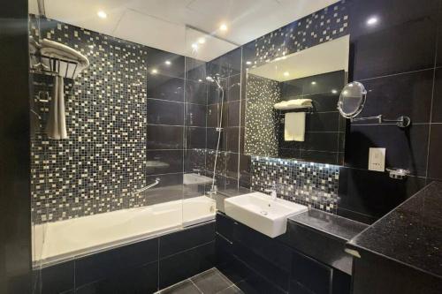 迪拜DAMAC Voleo In Business Bay的一间带水槽、浴缸和镜子的浴室