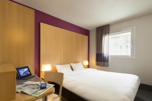 蒙彼利埃B&B HOTEL Montpellier Centre Le Millénaire的酒店客房配有一张床、一张书桌和一台笔记本电脑
