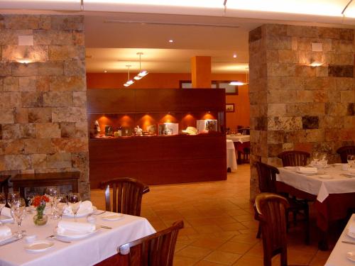 波凯兰特L'安国拉酒店的一间带白色桌椅的餐厅和一间厨房