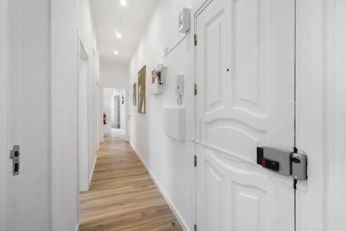 里斯本Smart Living Hub: Designer Spaces for Digital Nomads & Remote Workers的走廊设有白色的墙壁和木地板