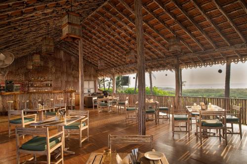 UtordaKenilworth Resort & Spa, Goa的大楼内的餐厅,配有木桌和椅子