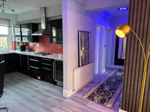 伯明翰Luxury 9ine Lush Jacuzzi Apartment with Balcony的厨房配有紫色墙壁、黑色橱柜和地毯。