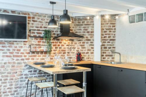 里尔Atypical flat in the centre of Lille.的厨房配有桌子和砖墙