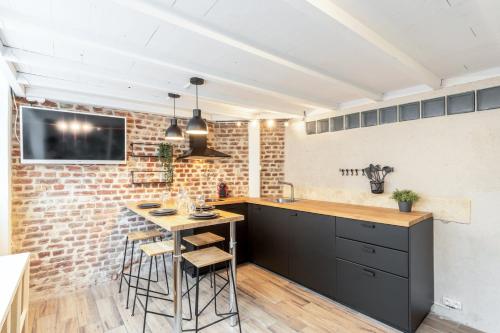 里尔Atypical flat in the centre of Lille.的厨房配有桌子和砖墙