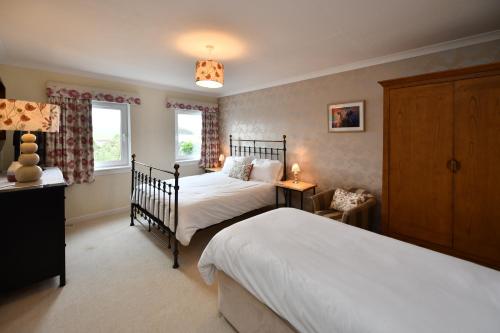 斯特兰拉尔Lochans Lodge的一间卧室设有两张床和两个窗户。