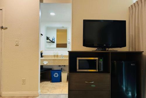 圣地亚哥圣地亚哥机场华美达酒店的浴室设有电视,橱柜上配有电视