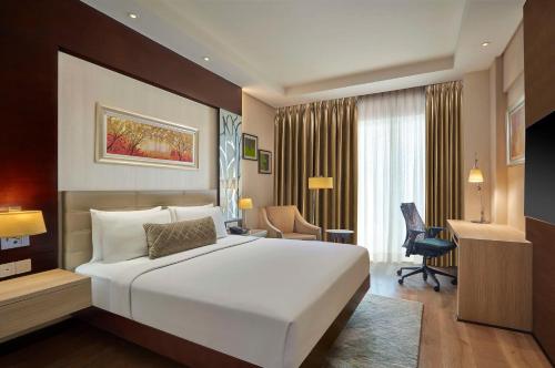 古尔冈DoubleTree by Hilton Gurugram Baani Square的卧室配有一张白色大床和一张书桌