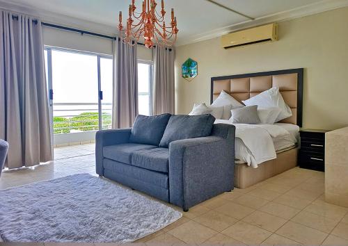 德班Glen Ashley Beach Villas的一间卧室配有一张床和一张蓝色的沙发