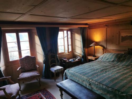 RougemontNouveau à Rougemont: Appartement dans Chalet 1830的一间卧室配有一张床、一把椅子和窗户。