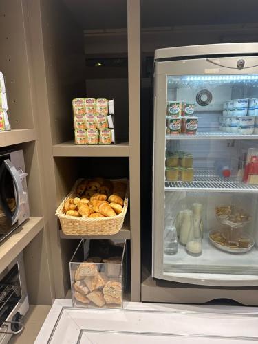 热讷维耶普瑞米尔巴黎西杰内维利尔经典酒店的开放式冰箱,带面包和一篮子食物