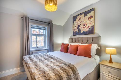 约克Middlethorpe Manor - No 3的一间卧室配有带橙色枕头的床和窗户。