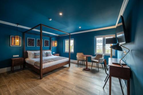英雄港Açores Autêntico Boutique Hotel的一间卧室设有蓝色的墙壁、一张床和一张书桌