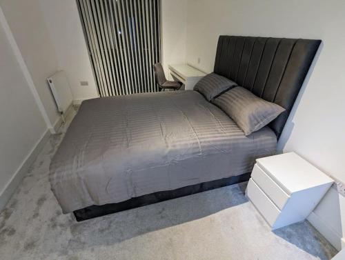 伦敦NEW Lux 1 or 2 Bed Flats + Car Park + 5min Tube + Fast WiFi的卧室配有一张大床和一张白色的桌子。