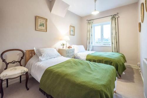伍德布里奇Mole Cottage, Orford的一间卧室设有两张床、一把椅子和一个窗户。