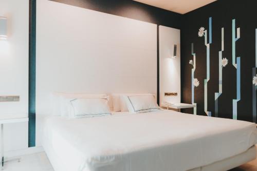 马拉加Hotel Málaga Nostrum Airport的卧室配有一张白色的床和黑色的墙壁