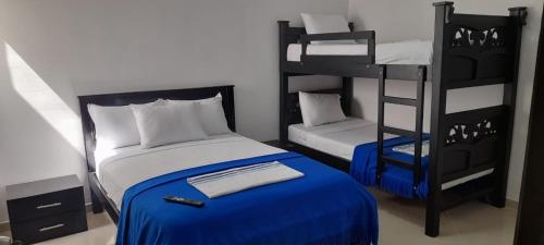 里奥阿查Hotel La Guajira - Centro Historico的一间卧室配有两张双层床和一张蓝色的床。