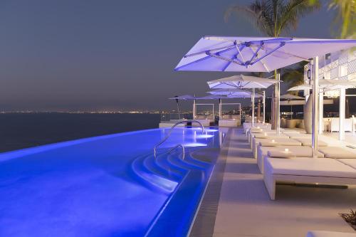 巴亚尔塔港姆赛酒店 - 仅限成人的游泳池在晚上提供躺椅和遮阳伞