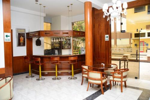 齐克拉约GLORIA PLAZA HOTEL的餐厅内的酒吧配有桌椅