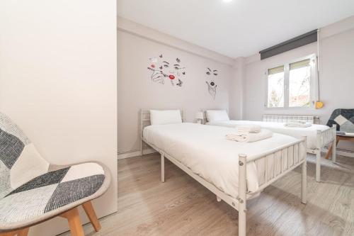马德里Elegant 6 pax apartment in Plaza Eliptica - SM17的白色卧室配有两张床和椅子