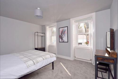 杰德堡Apartment in Scottish Borders的一间卧室配有一张床、一张书桌和两个窗户。