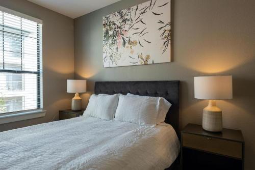 奥斯汀Landing Modern Apartment with Amazing Amenities (ID5843)的一间卧室配有一张带两盏灯和一幅画的床铺