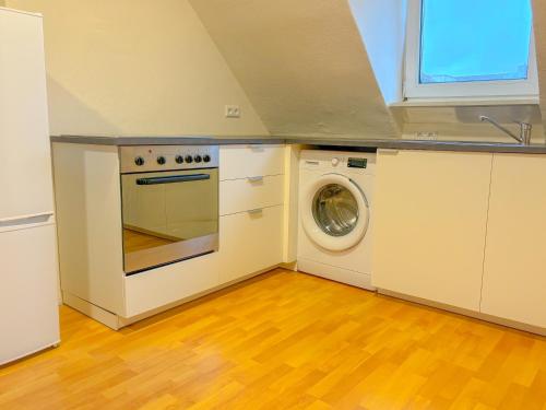 新乌尔姆Apartment über Neu Ulm's Dächern, 2 Schlafzimmer inkl. Stellplatz的厨房配有炉灶和洗衣机。