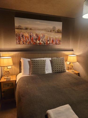 布罗德福德THE MOORINGS的一间卧室配有一张带两盏灯和一幅画的床铺