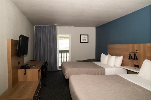 波特兰Quality Inn Portland Airport PDX的酒店客房设有两张床和电视。