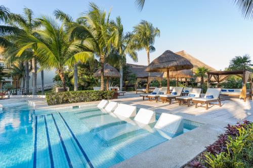 艾库玛尔TRS Yucatan Hotel - Adults Only的度假村的游泳池,配有椅子和遮阳伞
