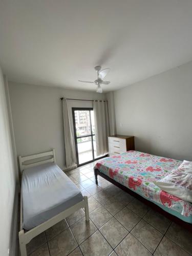 瓜拉派瑞Apartamento Praia do Morro com Churrasqueira, Cozinha Gourmet e Wifi的一间卧室配有一张床、一张桌子和一个窗户。